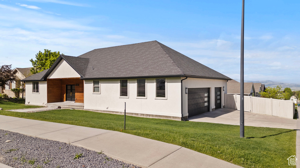 View of front of house with driveway, an attached garage, a shingled roof, and stucco siding