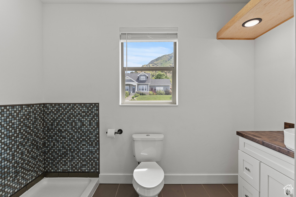 Full bathroom featuring baseboards, vanity, tiled shower, tile patterned flooring, and toilet