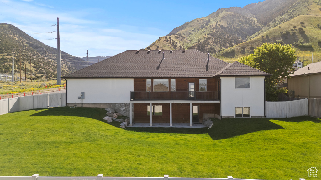 Rear view of property with a patio area, a mountain view, and a shingled roof