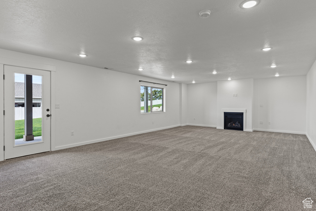 Unfurnished living room with recessed lighting, carpet flooring, a fireplace, and baseboards