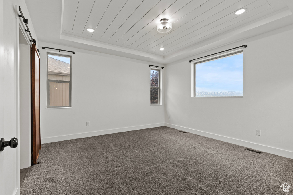 Carpeted empty room with a raised ceiling, recessed lighting, baseboards, and wooden ceiling