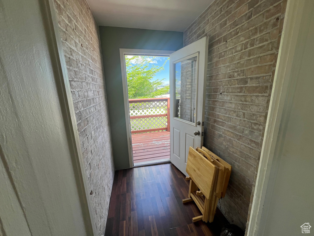 Doorway featuring radiator heating unit, dark wood finished floors, and brick wall