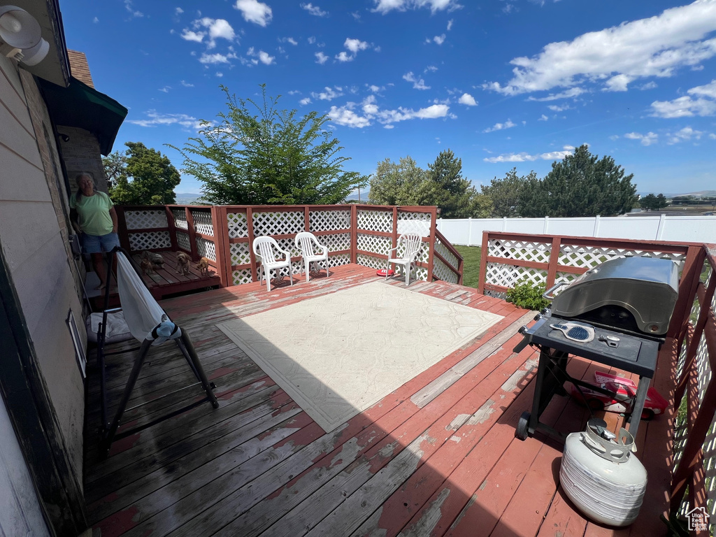 Wooden terrace with a fenced backyard and area for grilling