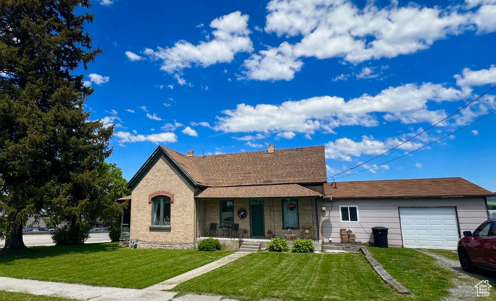 View of front of property with a garage, a front yard, covered porch, and driveway