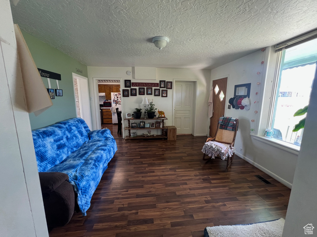 Living room with healthy amount of natural light, wood finished floors, a textured ceiling, and baseboards