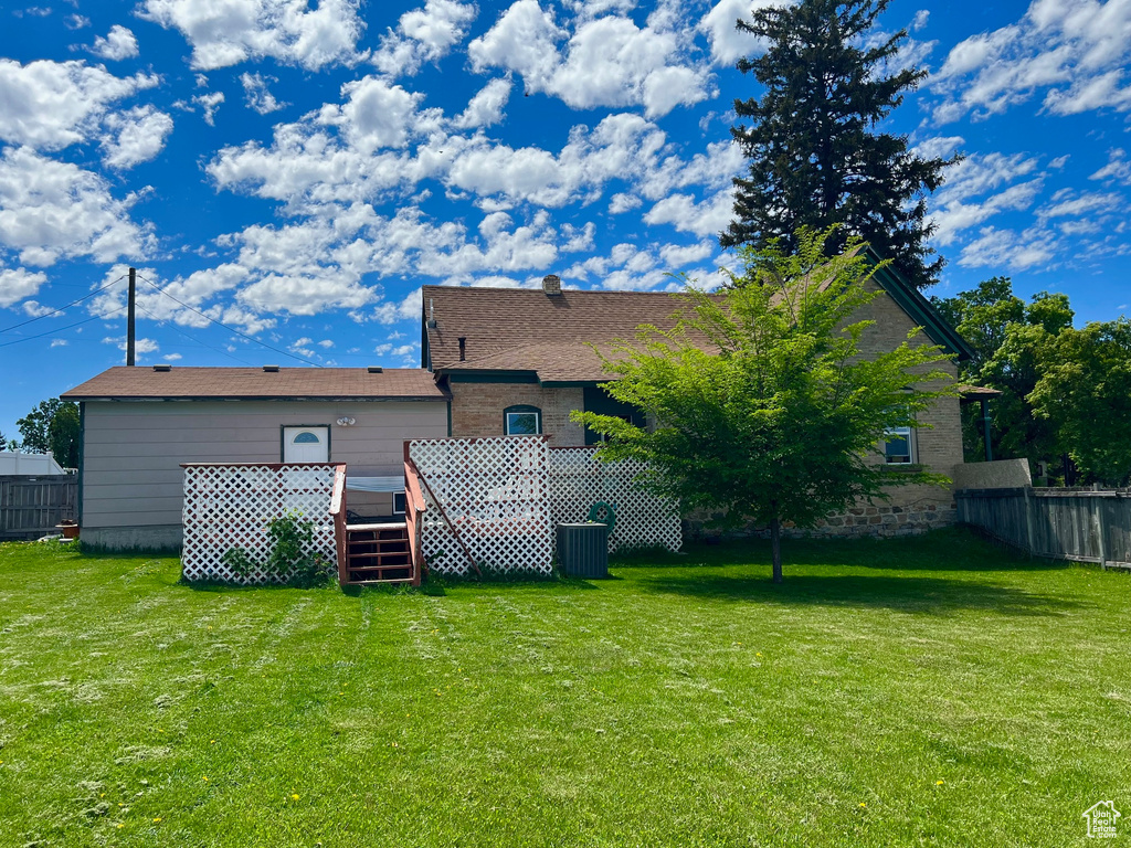 Back of property with a wooden deck and central AC unit