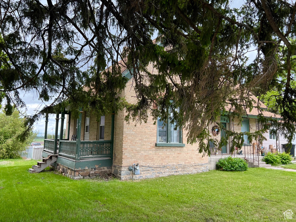 View of home's exterior featuring brick siding, a yard, and a porch