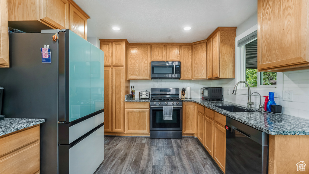 Kitchen featuring stainless steel appliances, a sink, dark wood-style flooring, decorative backsplash, and recessed lighting
