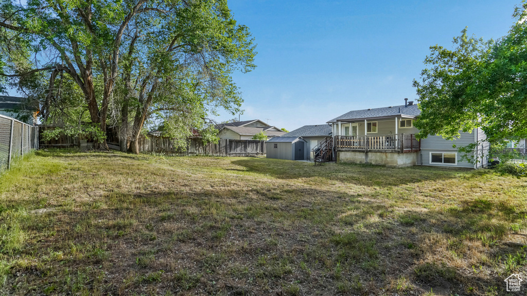 View of yard featuring a storage shed, an outbuilding, and a deck