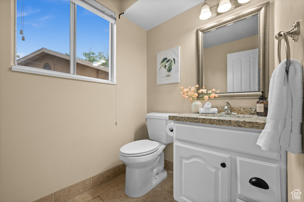 Bathroom with baseboards, vanity, tile patterned flooring, and toilet