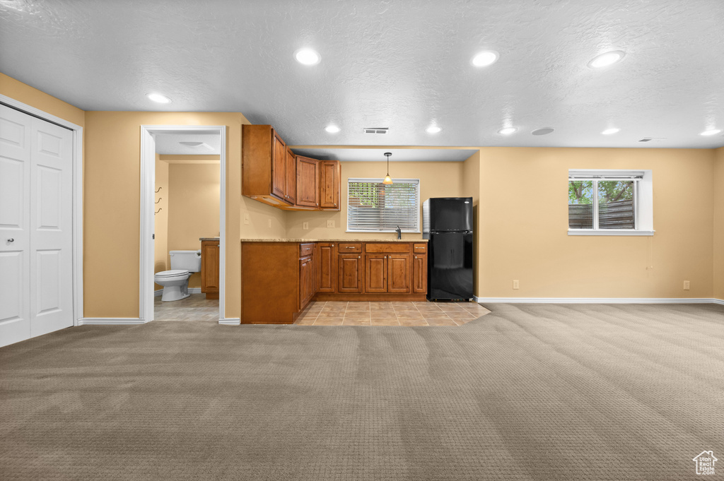 Kitchen with freestanding refrigerator, light colored carpet, recessed lighting, baseboards, and brown cabinets