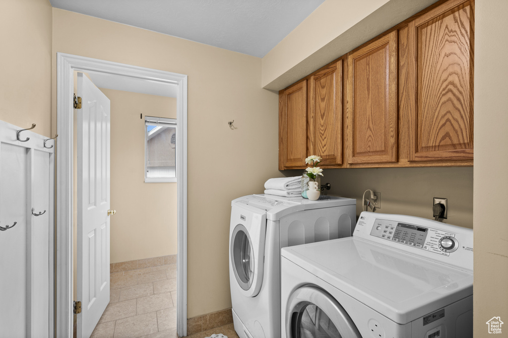 Laundry room featuring cabinet space, washing machine and clothes dryer, baseboards, and light tile patterned flooring