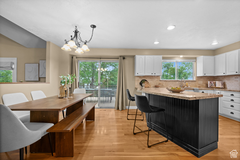 Kitchen featuring white cabinetry, light stone counters, backsplash, light wood-style floors, and recessed lighting