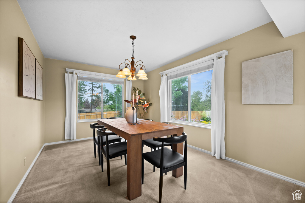 Dining room with a chandelier, light carpet, and baseboards