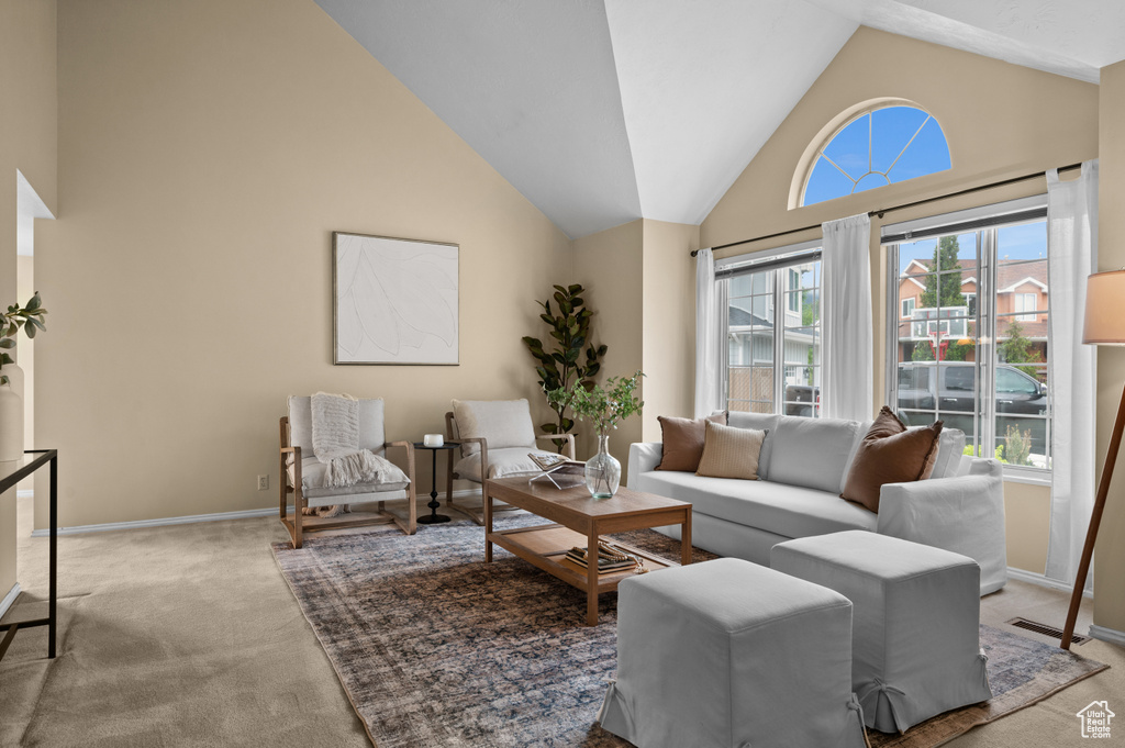Living room with carpet flooring, high vaulted ceiling, and baseboards