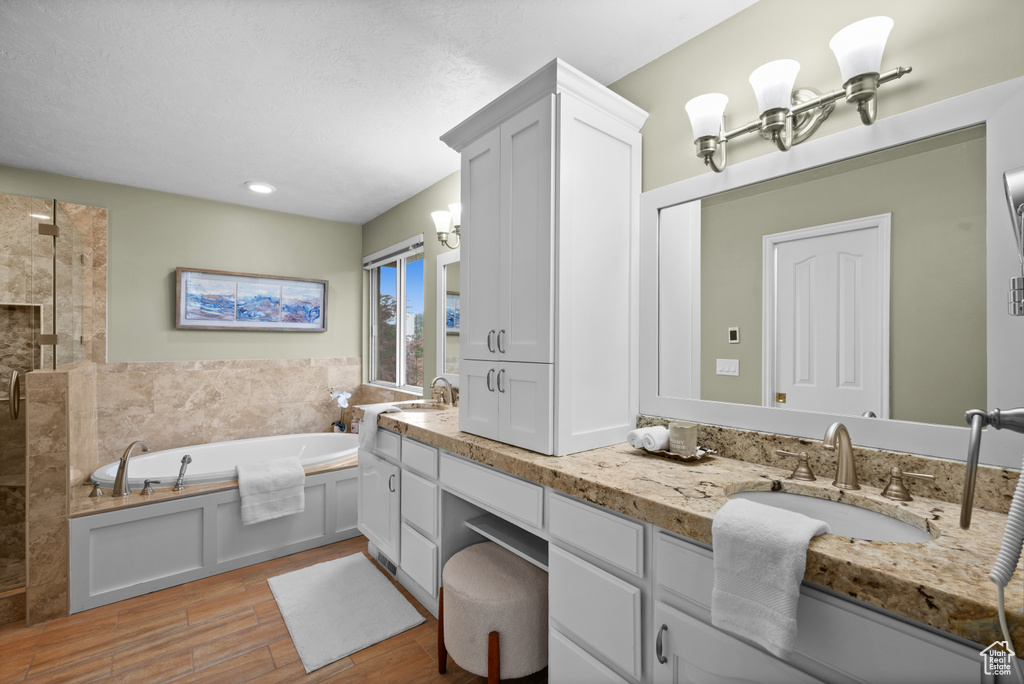 Full bathroom featuring a bath, wood finished floors, tiled shower, double vanity, and recessed lighting