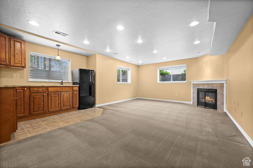 Unfurnished living room featuring light carpet, a fireplace, recessed lighting, baseboards, and a textured ceiling