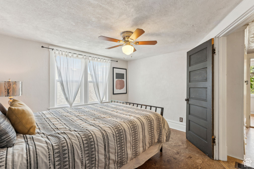 Carpeted bedroom with a textured ceiling and a ceiling fan