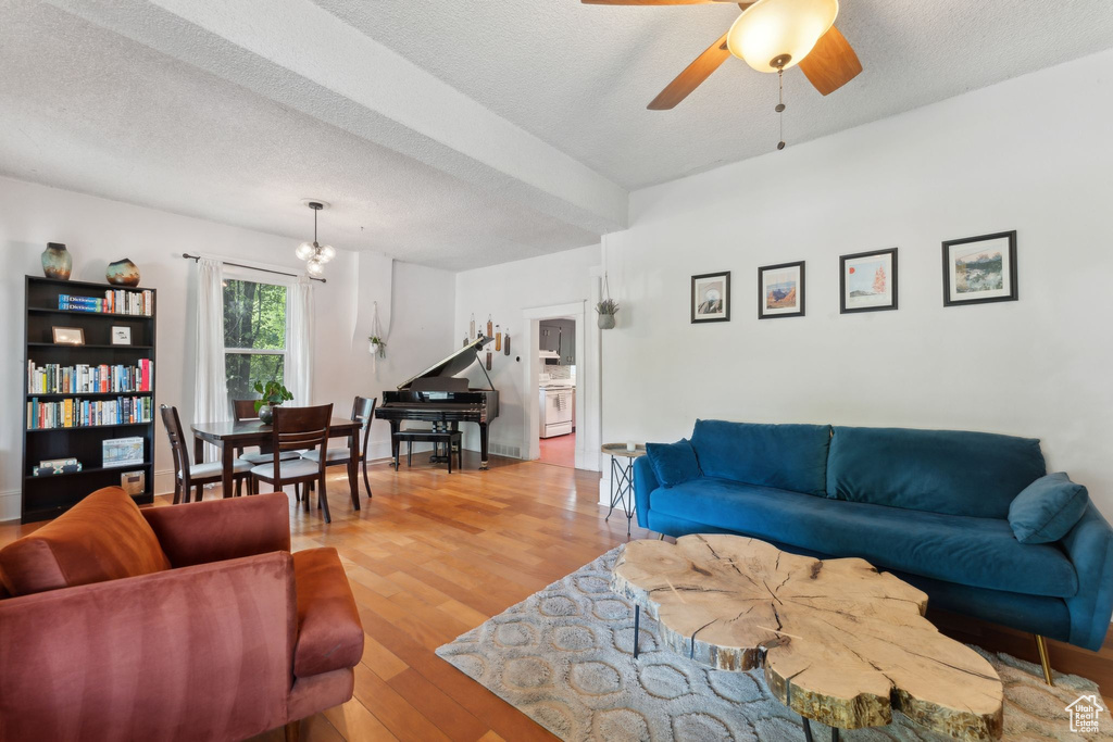 Living room with wood finished floors, a ceiling fan, a textured ceiling, and a chandelier