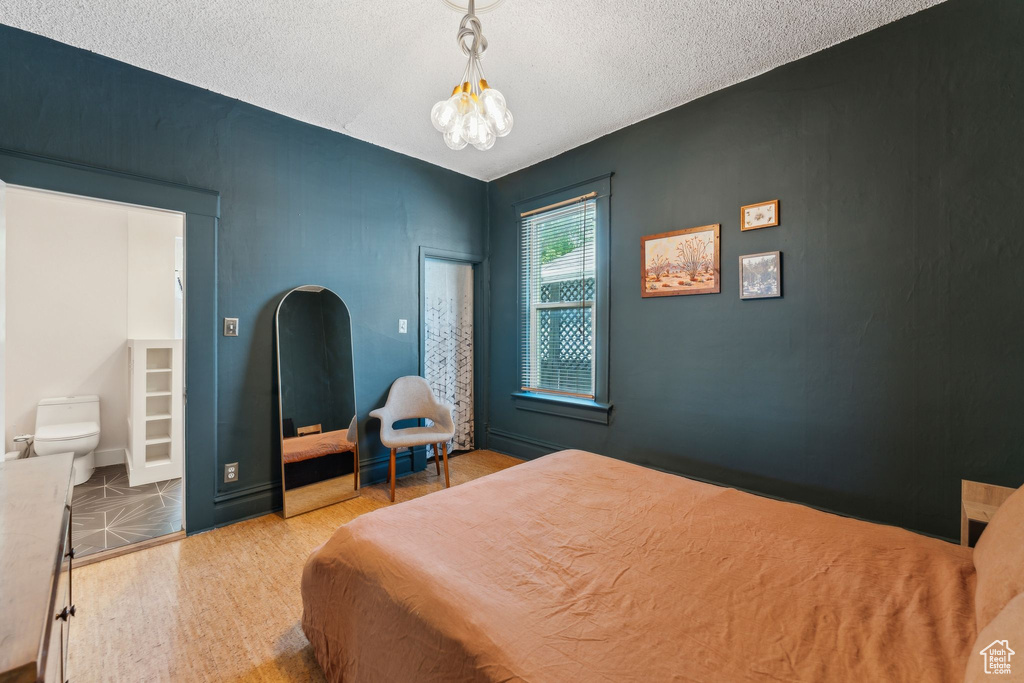 Bedroom featuring wood finished floors, a textured ceiling, and a chandelier