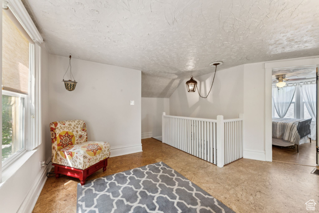 Sitting room featuring a textured ceiling, baseboards, and a ceiling fan