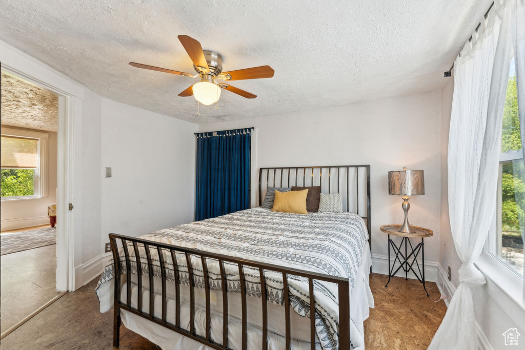 Bedroom with a textured ceiling, a ceiling fan, and baseboards