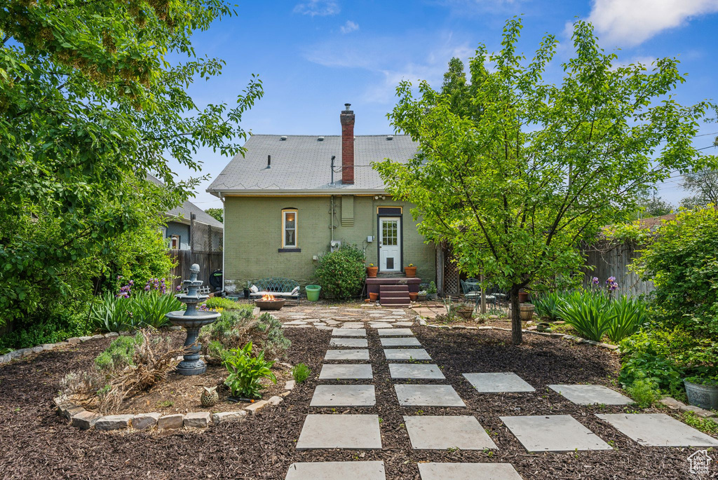 Rear view of property featuring fence, a chimney, and brick siding