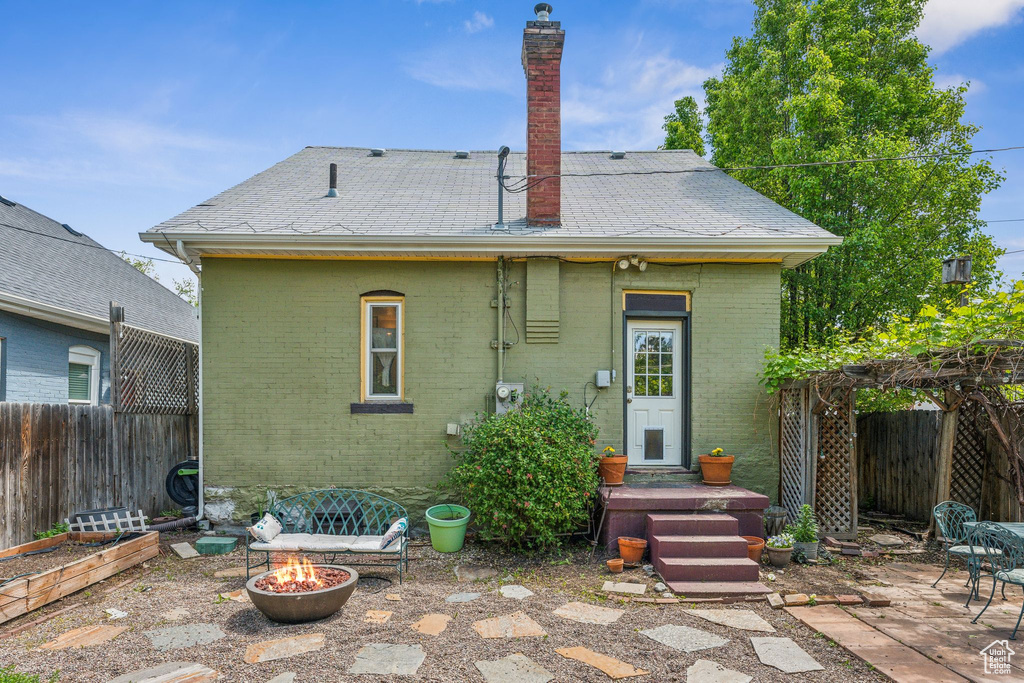 Back of property with an outdoor fire pit, brick siding, fence, and a patio area