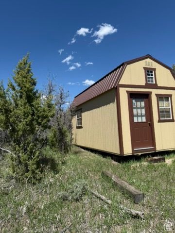 View of property exterior with metal roof, an outbuilding, a gambrel roof, and a storage shed