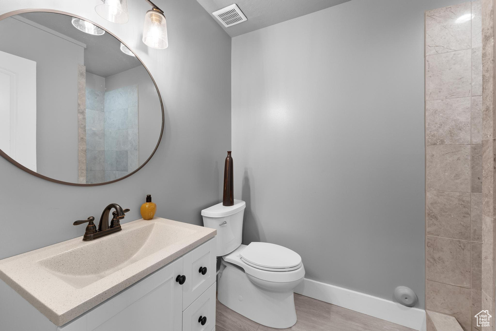 Bathroom featuring toilet, wood finished floors, vanity, and baseboards
