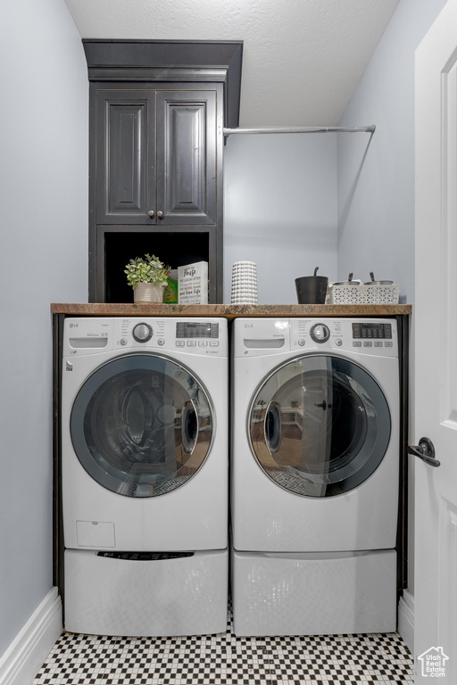 Washroom with washer and clothes dryer, cabinet space, tile patterned floors, and baseboards