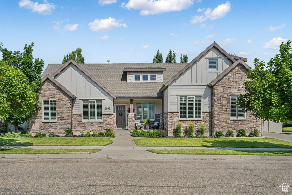 Craftsman house with board and batten siding, stone siding, a shingled roof, and a front yard