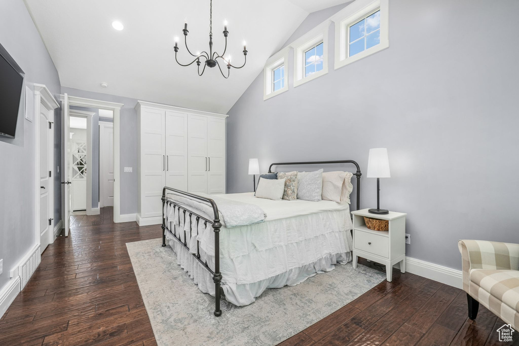 Bedroom with dark wood finished floors, high vaulted ceiling, and a chandelier