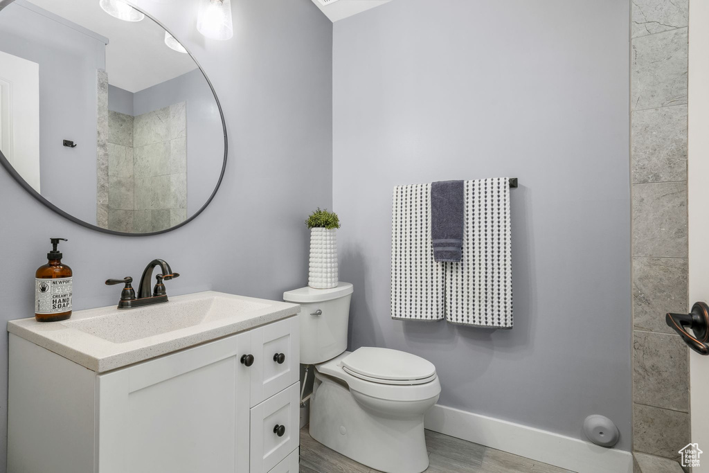 Full bath with wood finished floors, vanity, and a tile shower