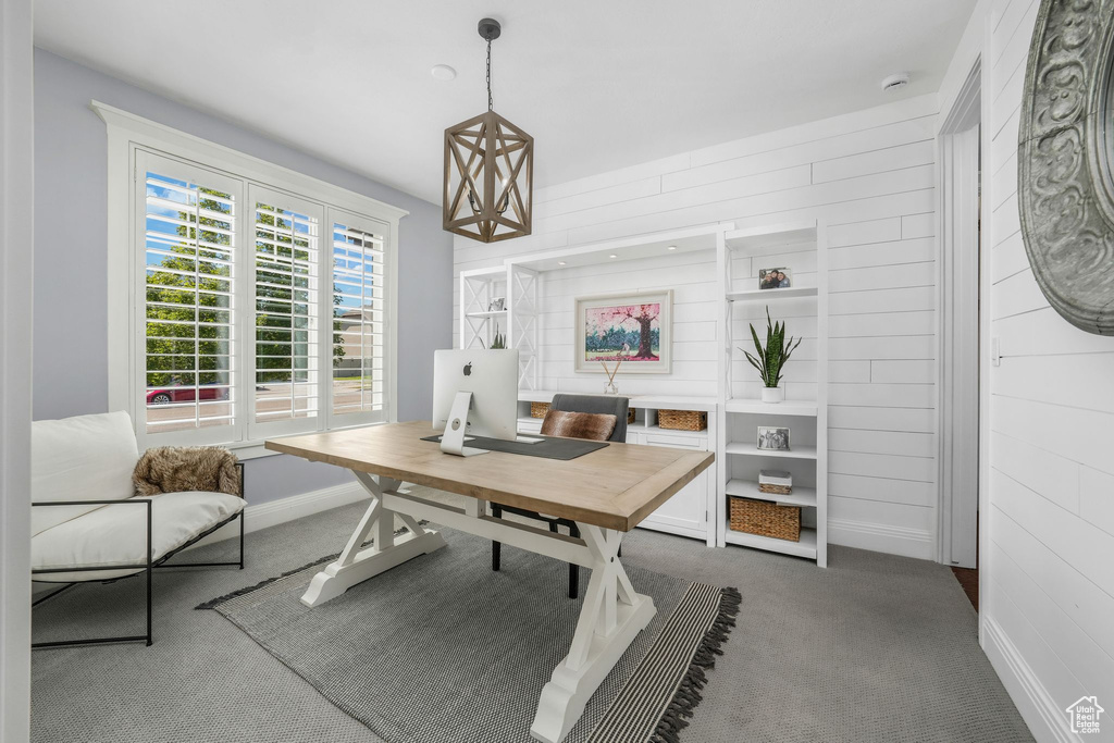 Home office with carpet flooring and wooden walls