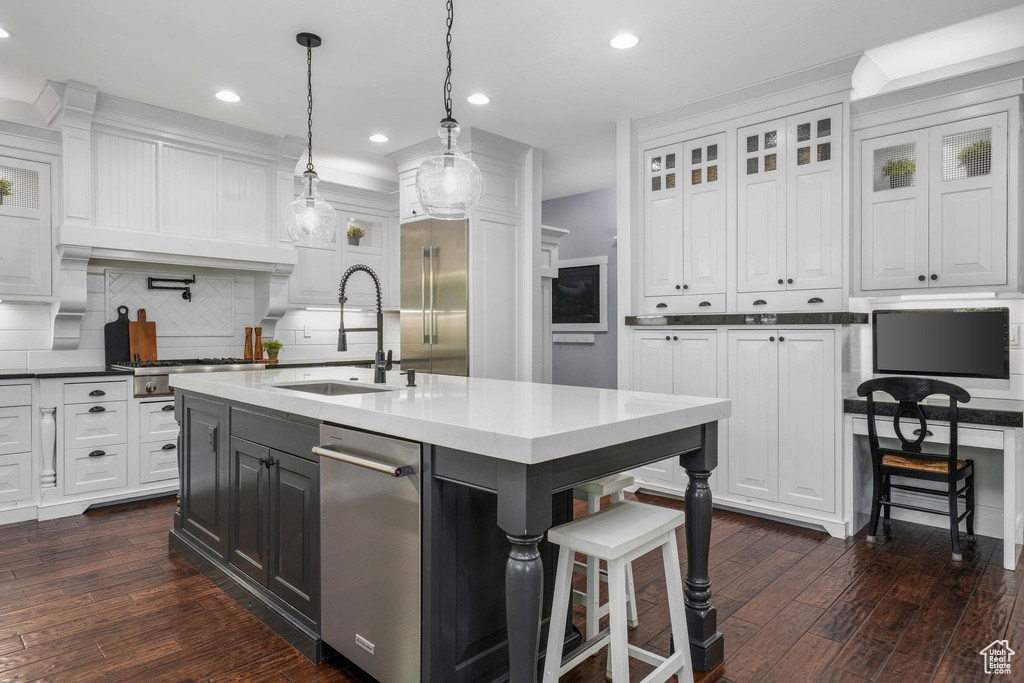 Kitchen with white cabinetry, dark wood-style flooring, tasteful backsplash, stainless steel appliances, and recessed lighting