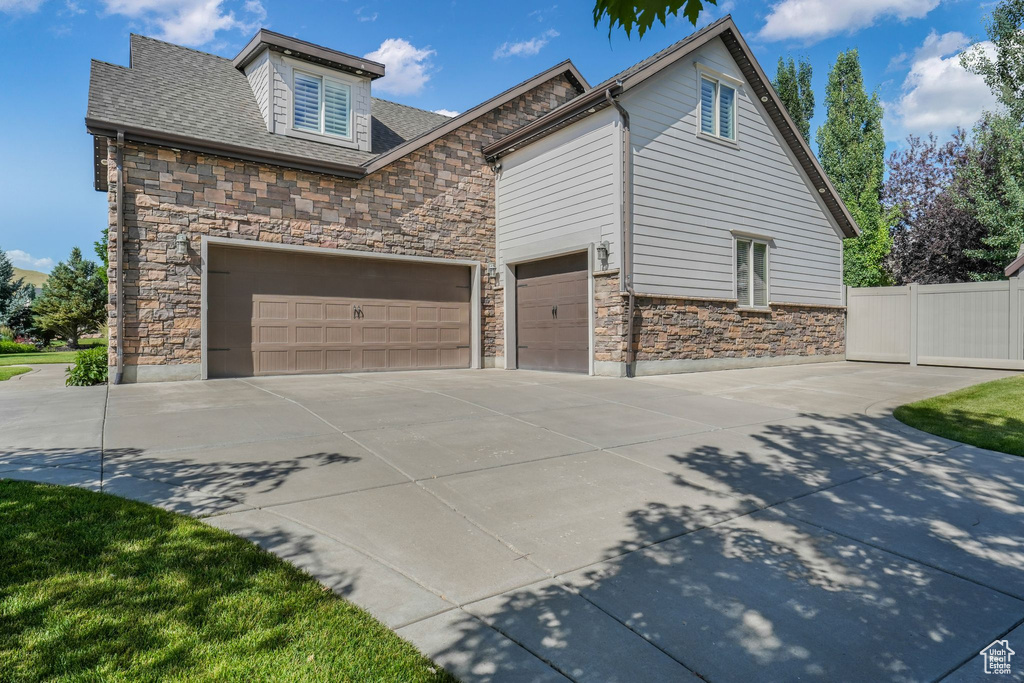 View of property exterior featuring stone siding, driveway, and a garage