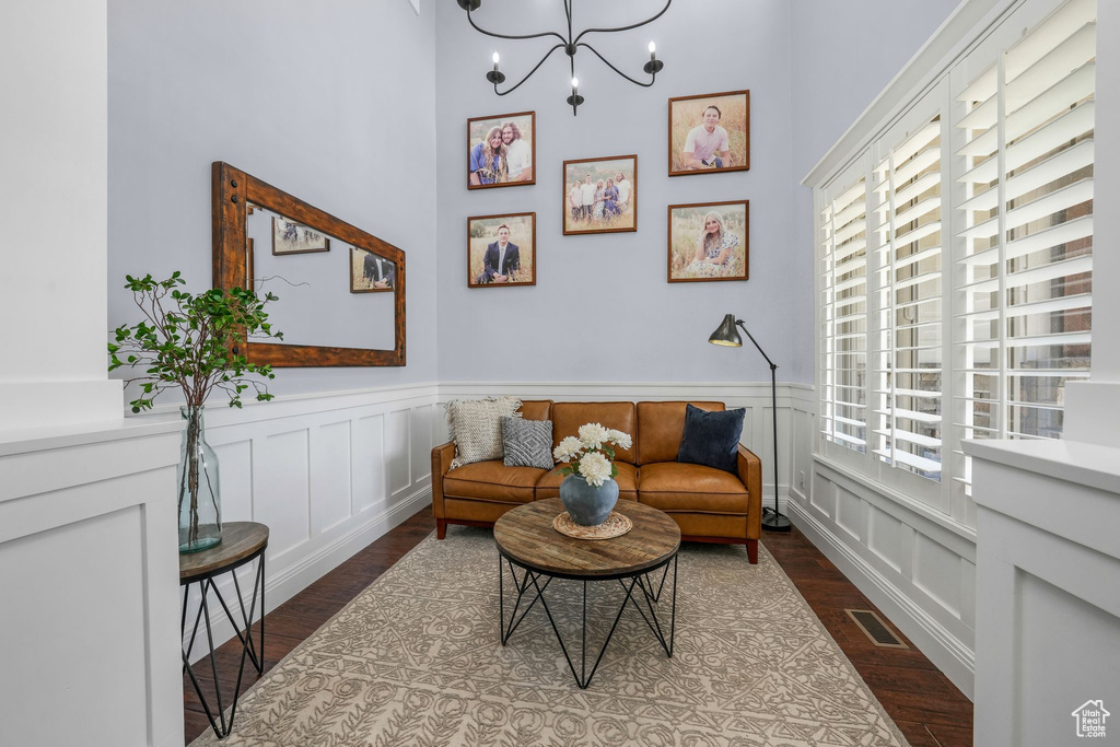 Sitting room with wood finished floors, a chandelier, wainscoting, and a decorative wall