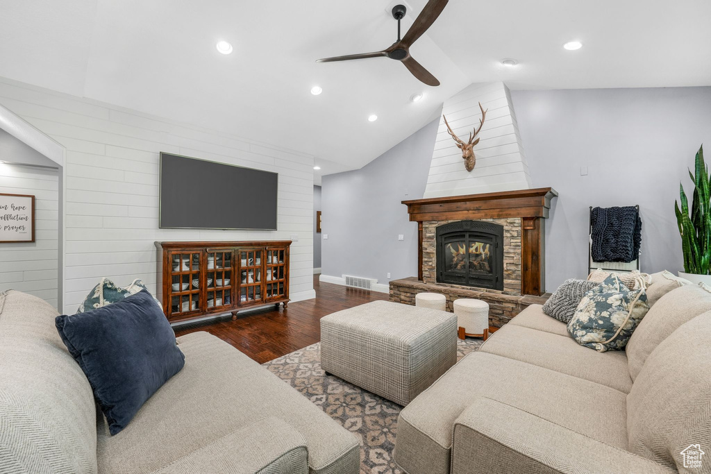 Living room with a ceiling fan, wood finished floors, a stone fireplace, recessed lighting, and wooden walls