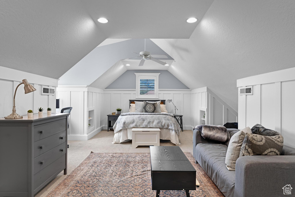 Bedroom featuring a decorative wall, vaulted ceiling, a ceiling fan, light colored carpet, and a wainscoted wall