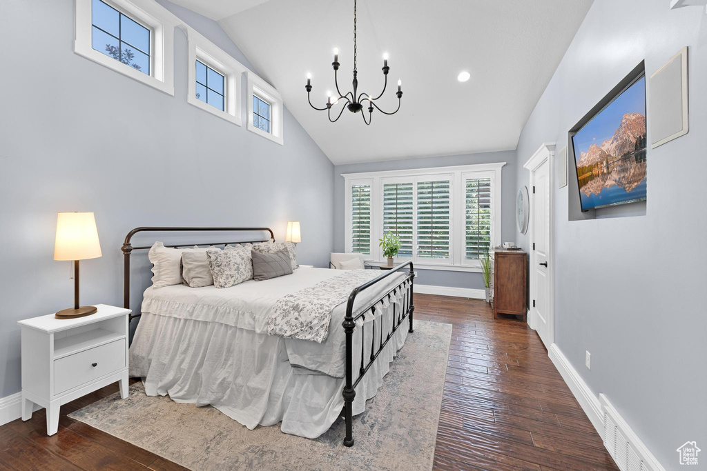 Bedroom featuring a chandelier, multiple windows, dark wood finished floors, and high vaulted ceiling