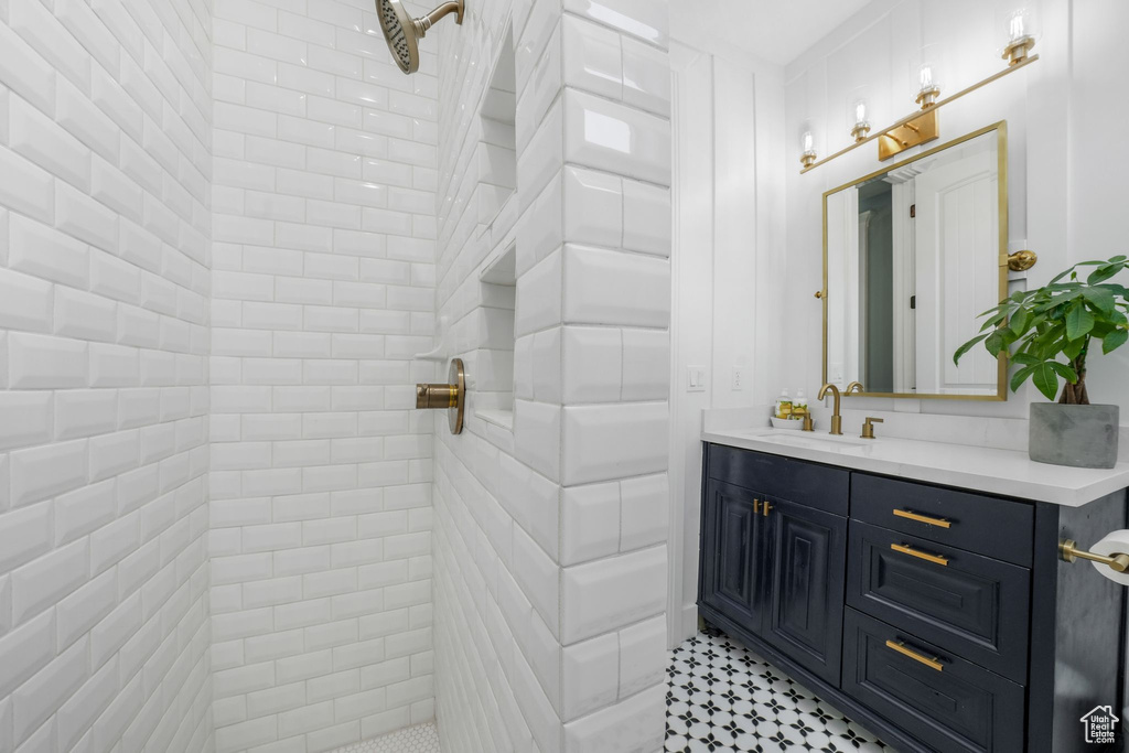 Full bath featuring tiled shower and vanity