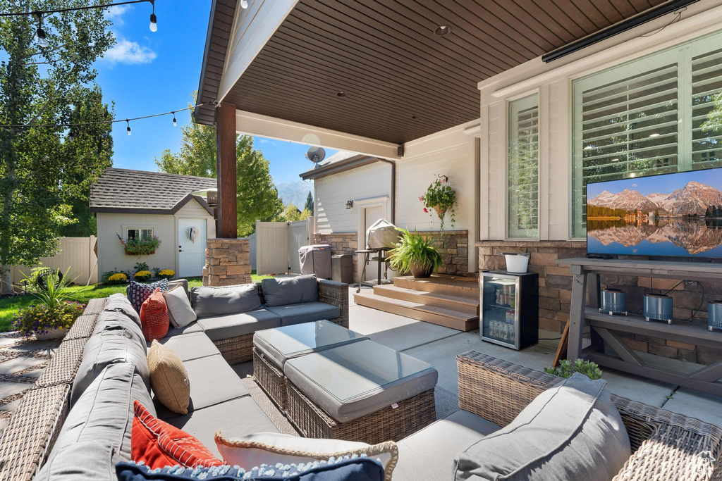 View of patio with outdoor lounge area, an outbuilding, fence, and wine cooler