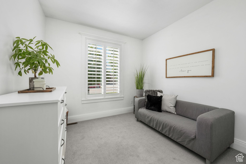 Living area with baseboards and light carpet