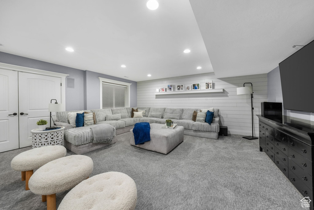 Living room with carpet flooring, recessed lighting, and wooden walls