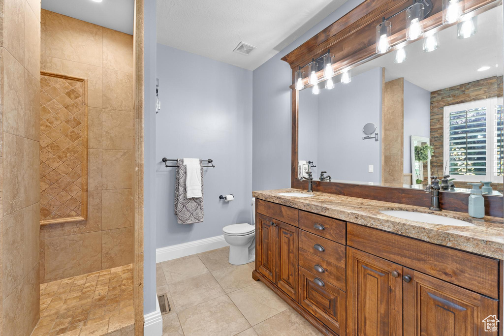 Full bath with walk in shower, double vanity, toilet, baseboards, and tile patterned flooring