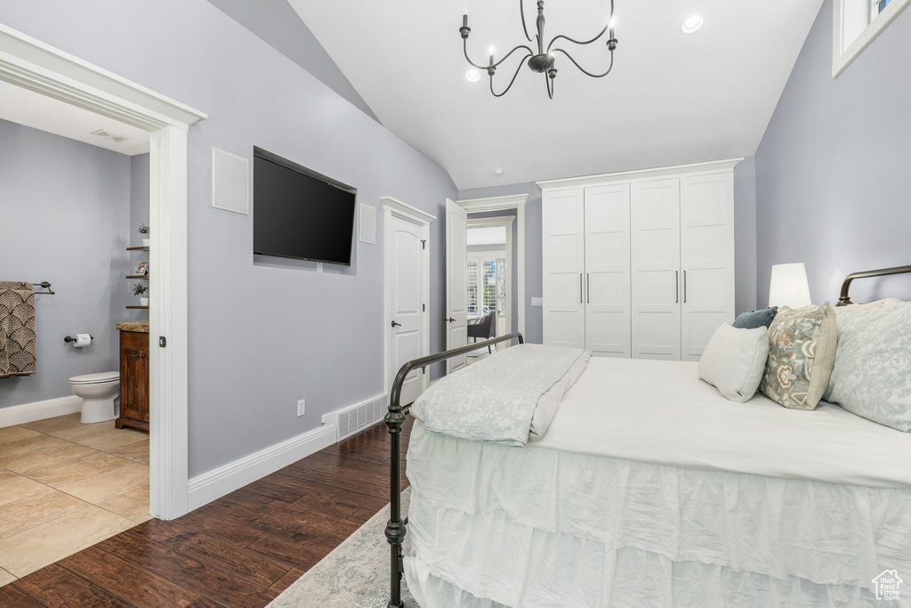 Bedroom featuring lofted ceiling, a chandelier, ensuite bathroom, wood finished floors, and a closet