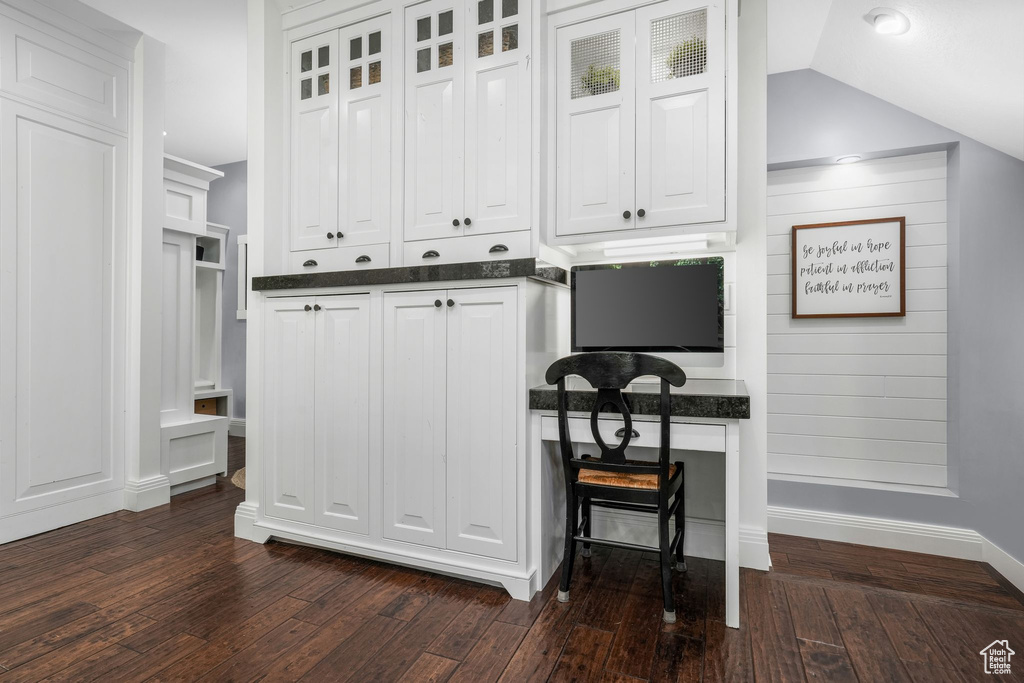 Kitchen featuring dark countertops, white cabinets, dark wood-style flooring, and glass insert cabinets