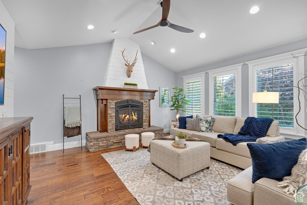 Living room featuring wood finished floors, a stone fireplace, ceiling fan, plenty of natural light, and recessed lighting