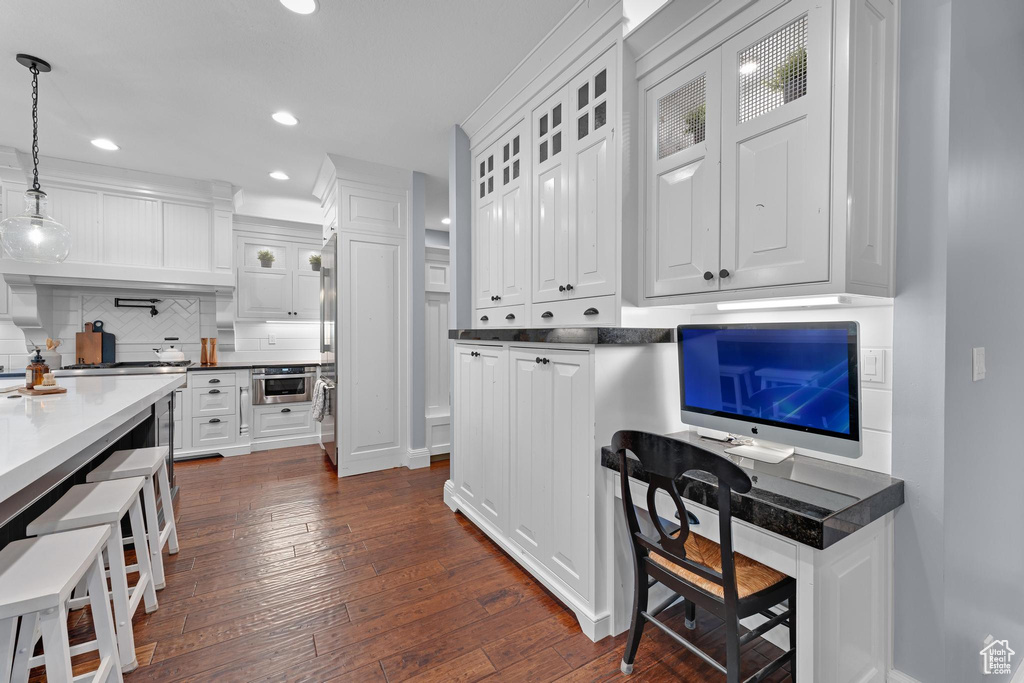 Kitchen featuring white cabinets, decorative backsplash, recessed lighting, dark wood finished floors, and glass insert cabinets
